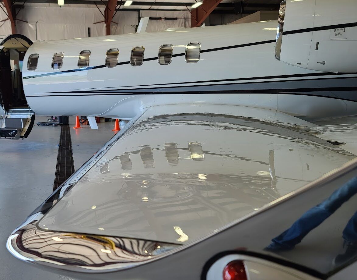Close-up of a white and silver airplane wing and fuselage inside a hangar.