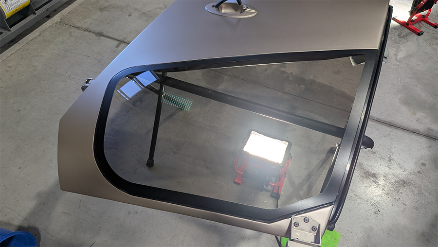 Tan car door with black trim and window.