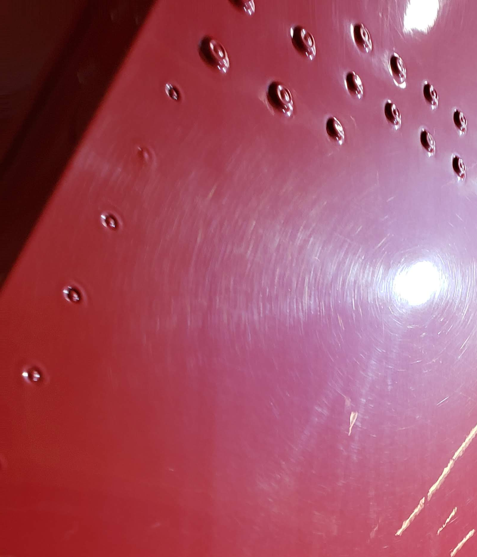 Red surface with circular indentations and swirling scratches.