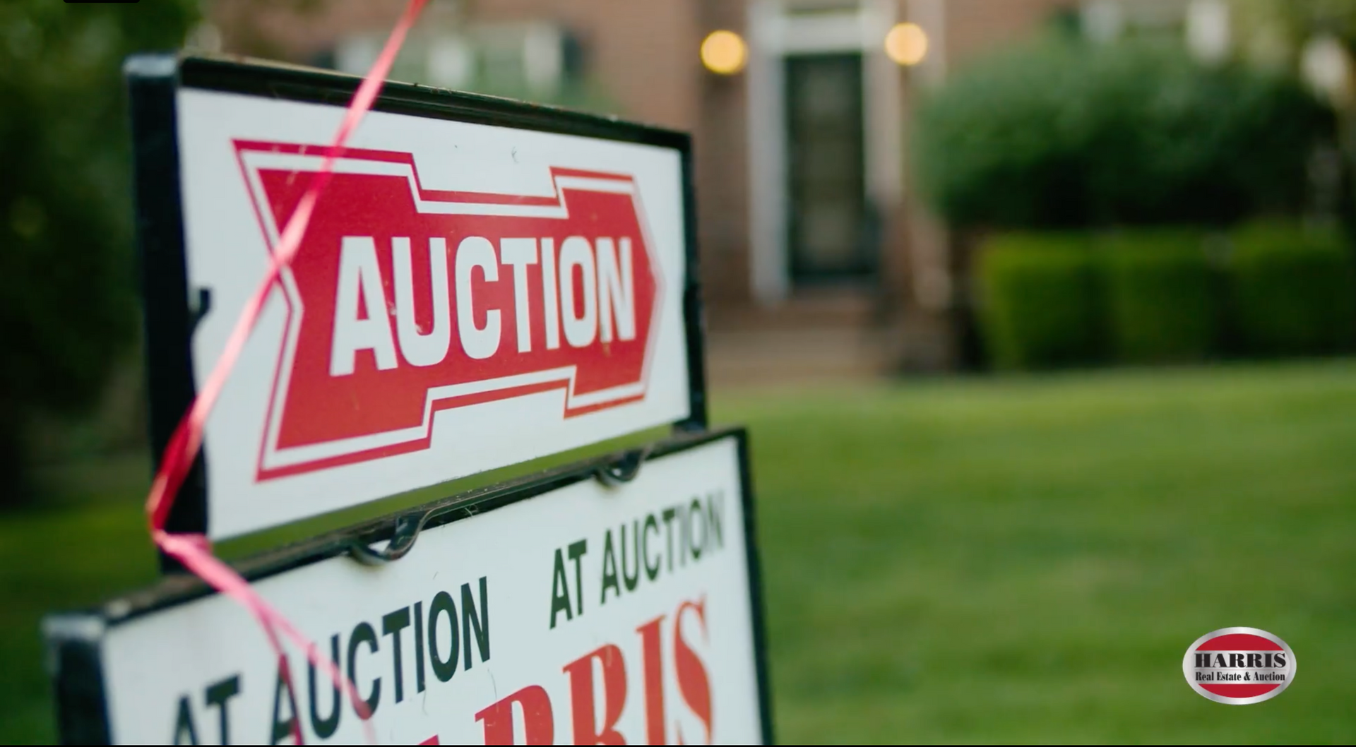 Auction signs posted on a lawn, with a red and white “AUCTION” sign in front.
