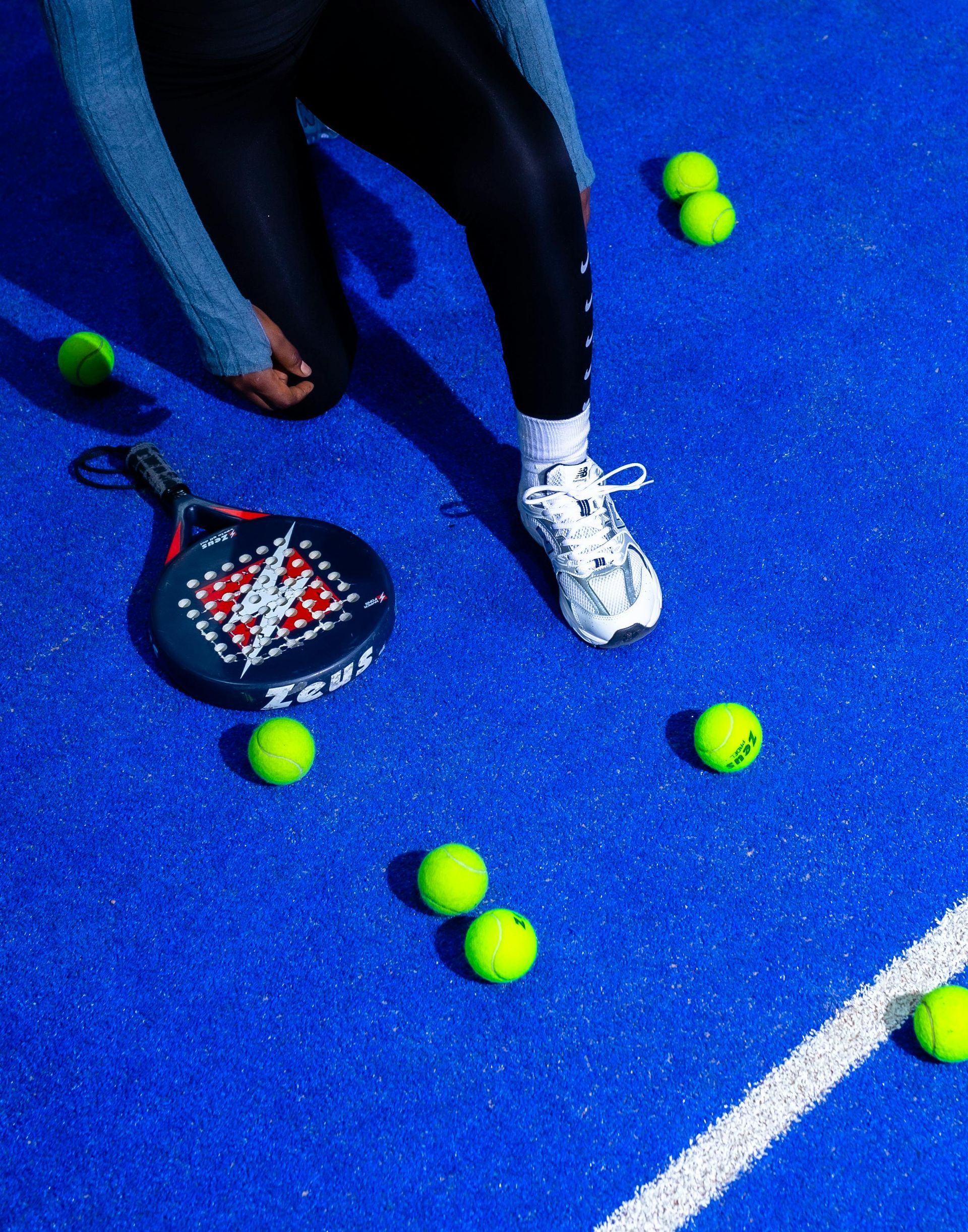 Un hombre con camisa verde azulado y gorra blanca sonríe al teléfono, sosteniendo una paleta y una mochila.