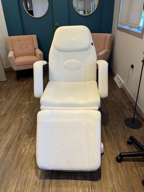 White spa chair with armrests and footrest in a room with pink armchairs and mirrors.