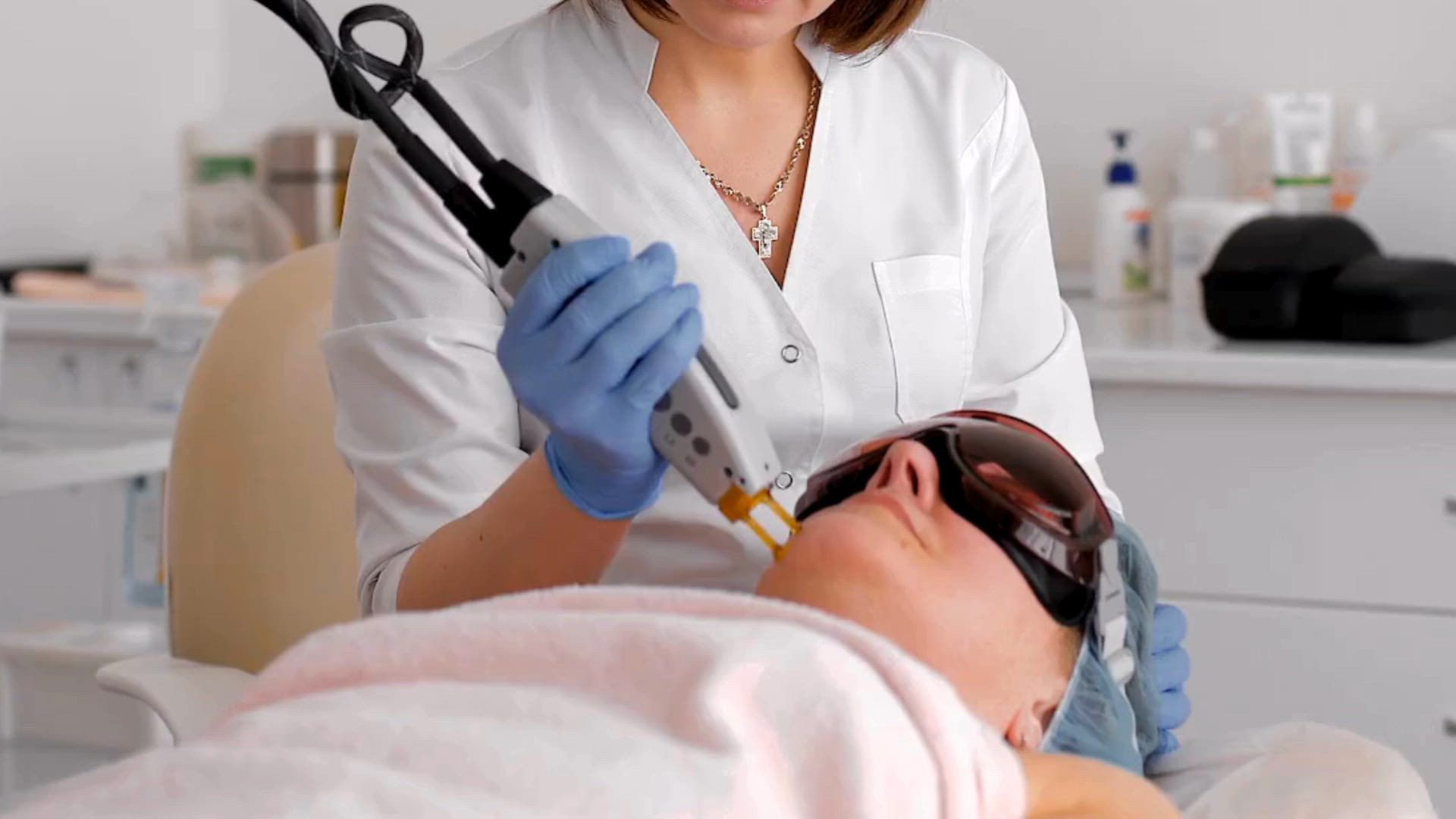 A professional performs a cosmetic laser treatment on a person wearing protective eyewear in a clinical setting.