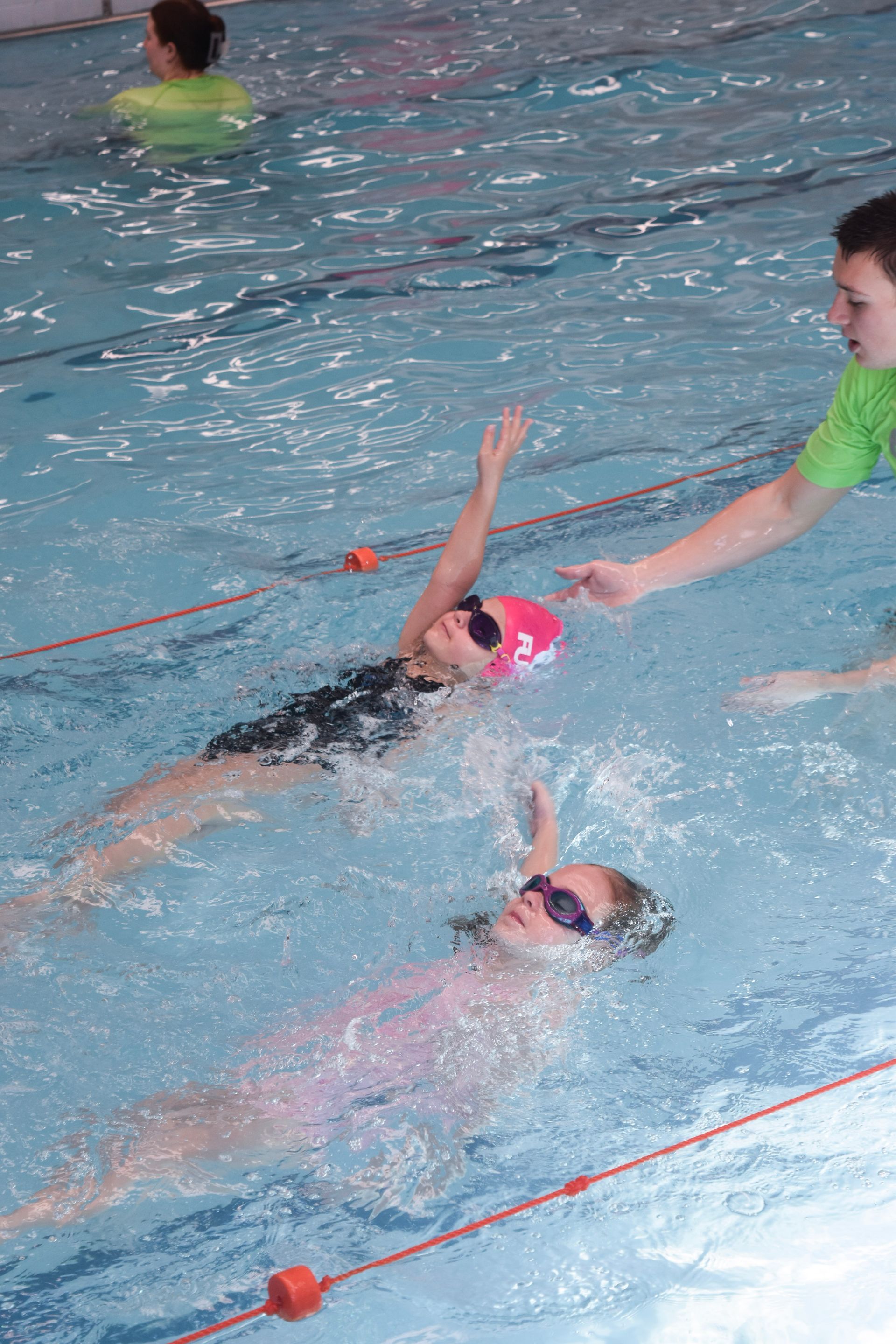 A group of children are swimming in a swimming pool.