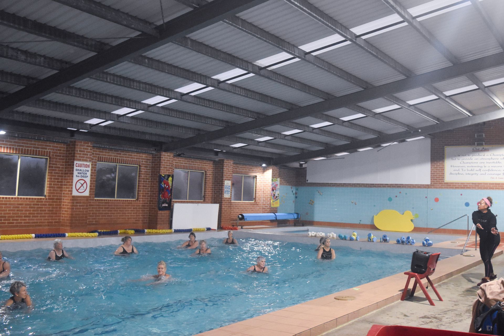 A group of people are swimming in a large indoor swimming pool.