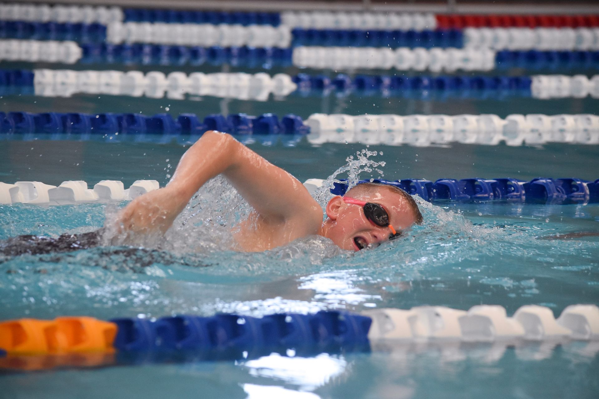 A young boy is swimming in a swimming pool.