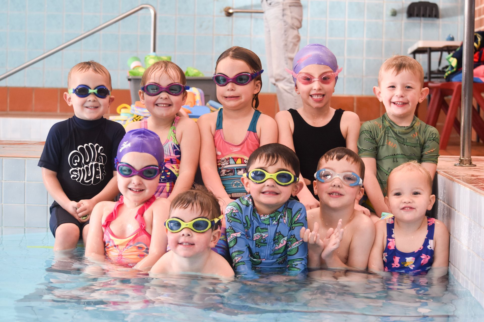 A group of children are posing for a picture in a swimming pool.