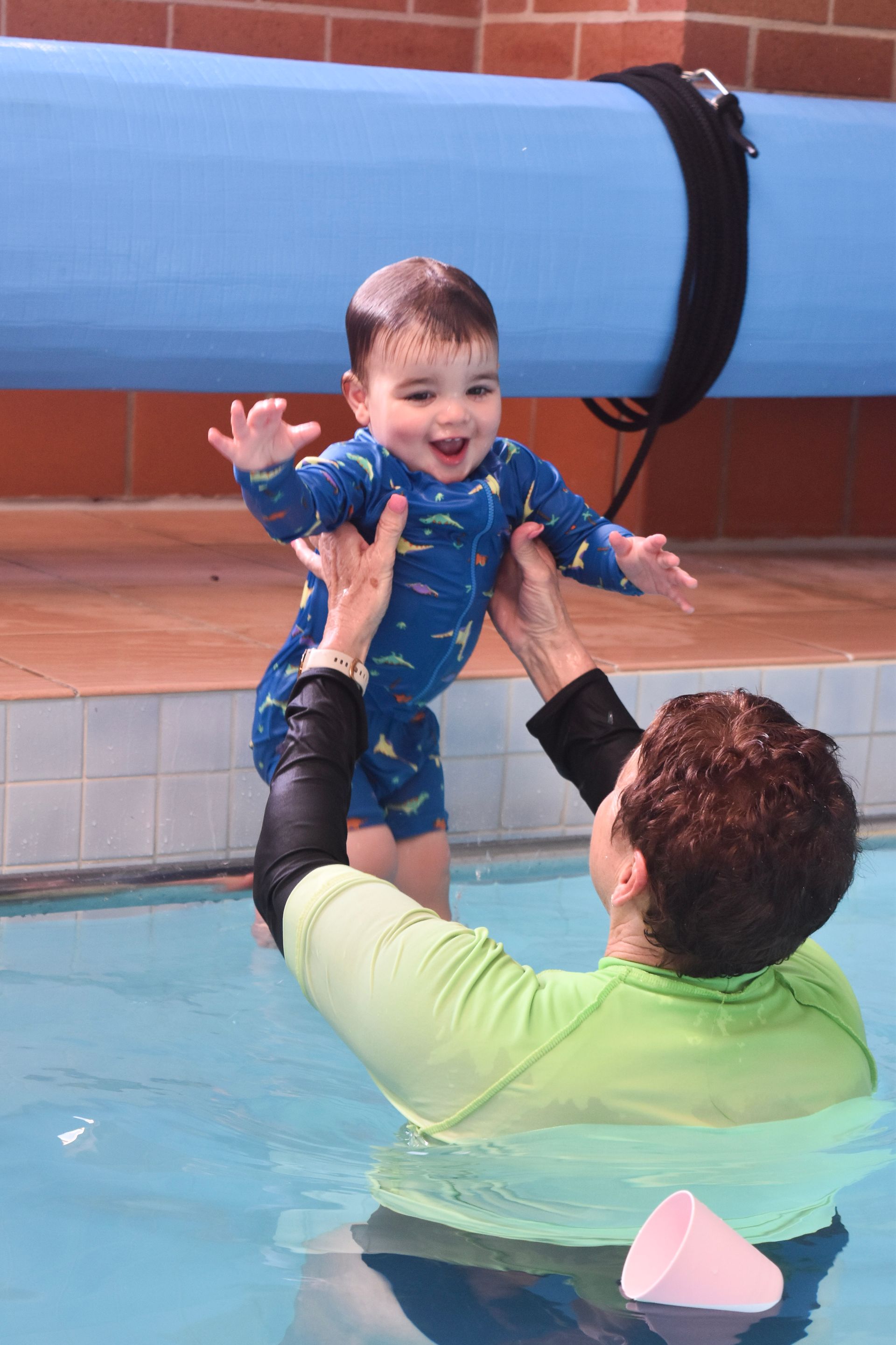 A woman is holding a baby in her arms in a swimming pool.