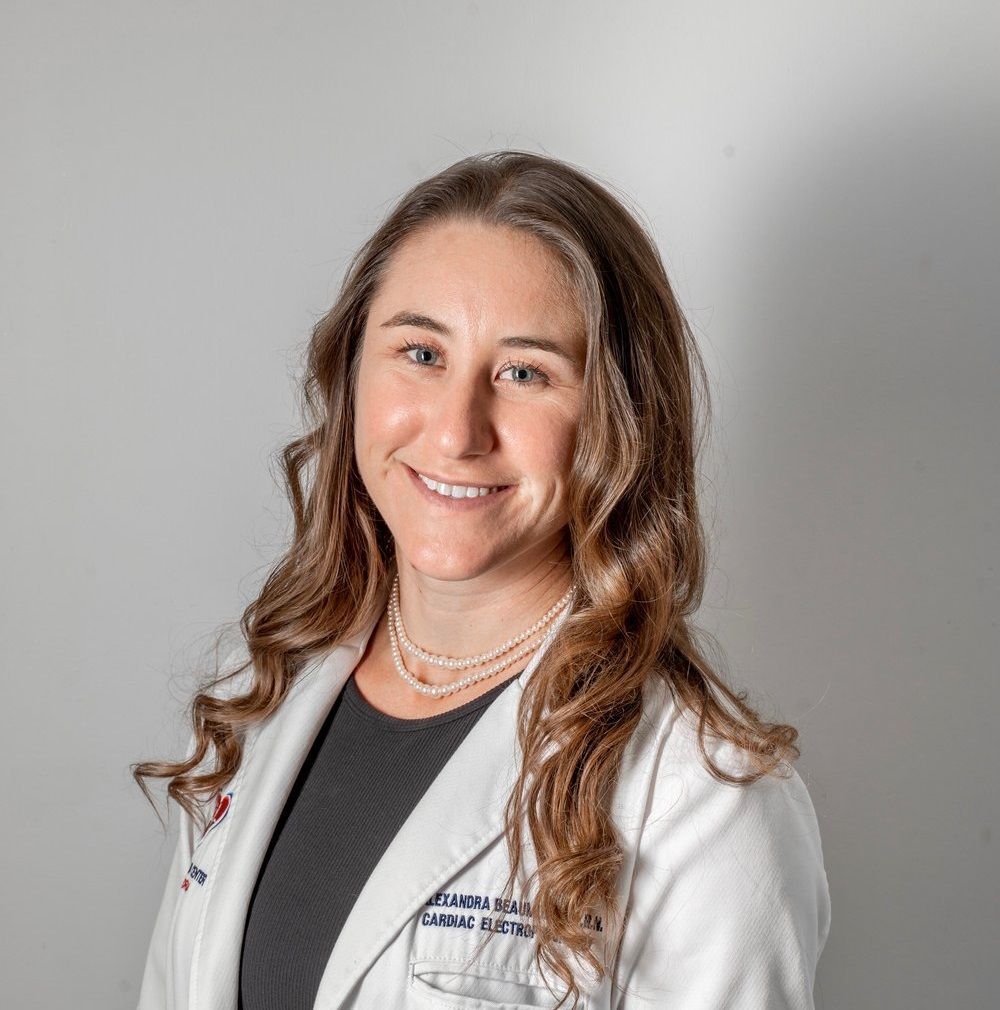 Smiling medical professional in a white coat against a gray background