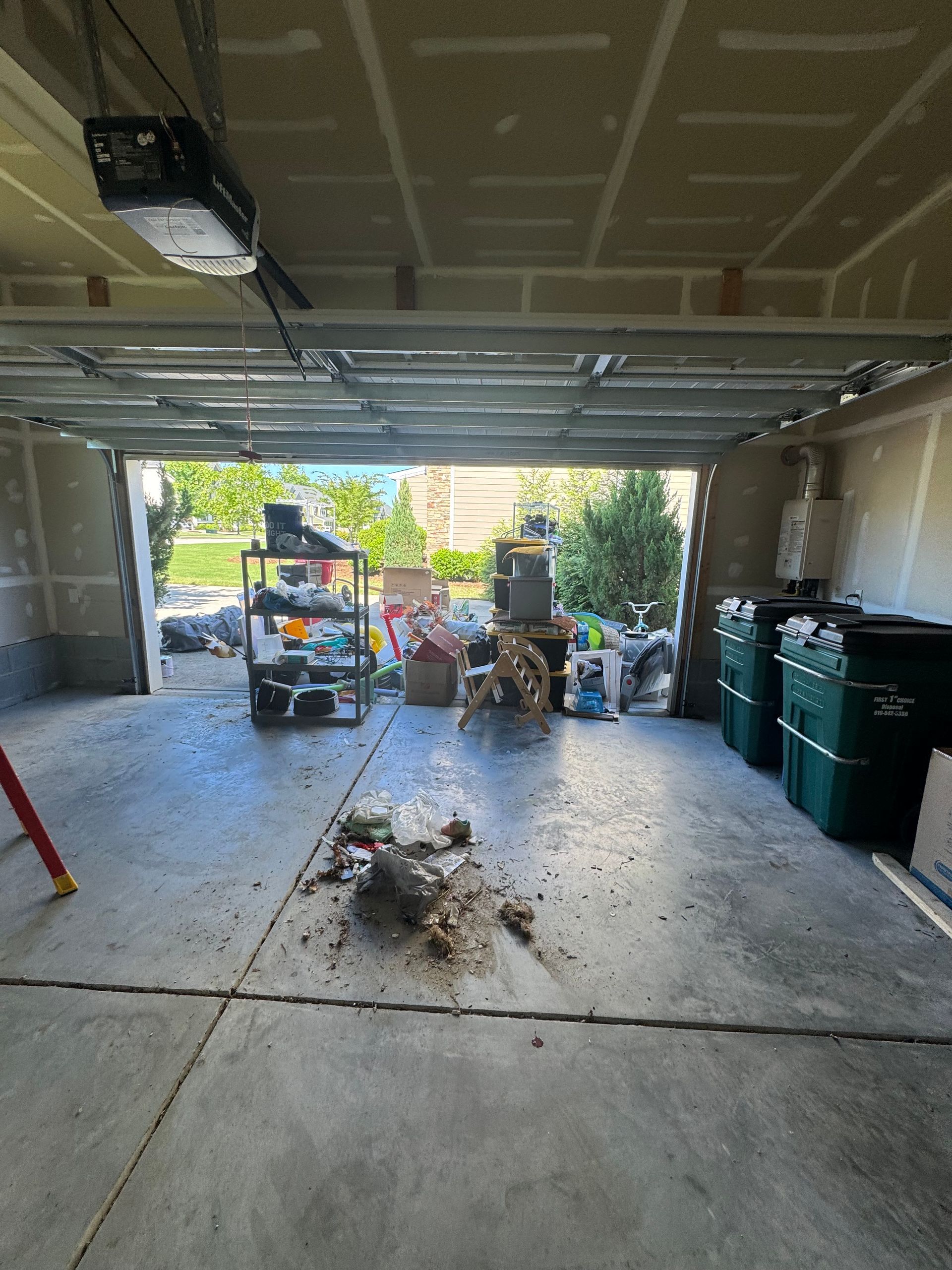 Open garage with clutter and a view to the outside. A debris pile in the foreground.