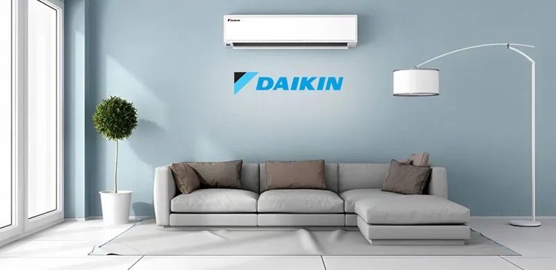 A living room with a couch and a daikin air conditioner on the wall.