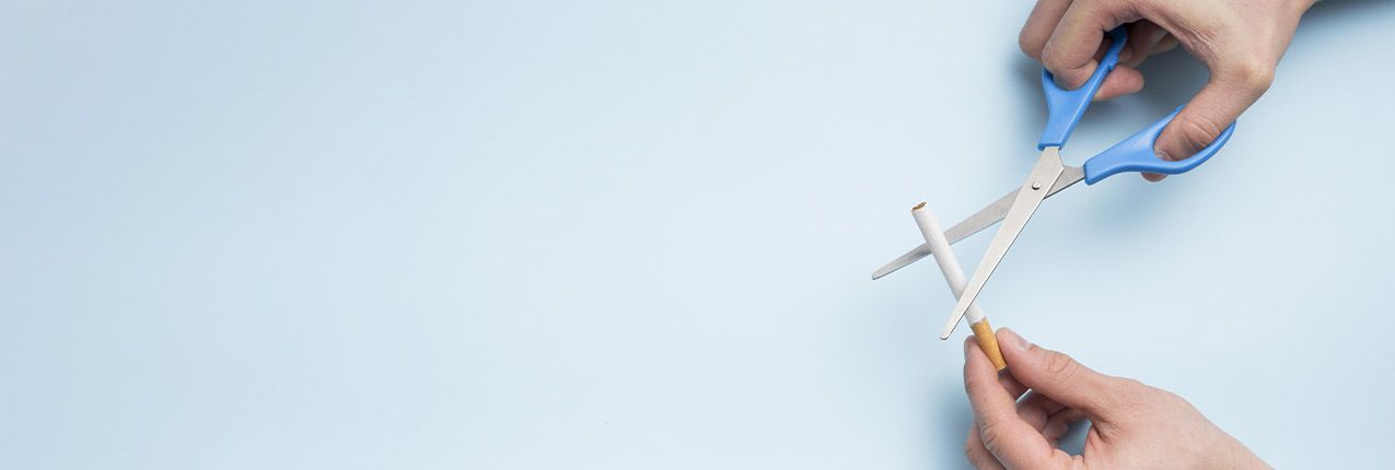 Hands using scissors to cut a cigarette in half