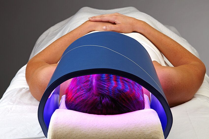 A woman is laying on a bed with a blue light on her head