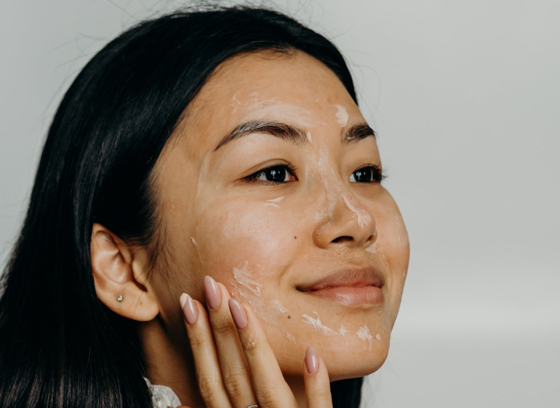 A woman is applying a cream to her face.