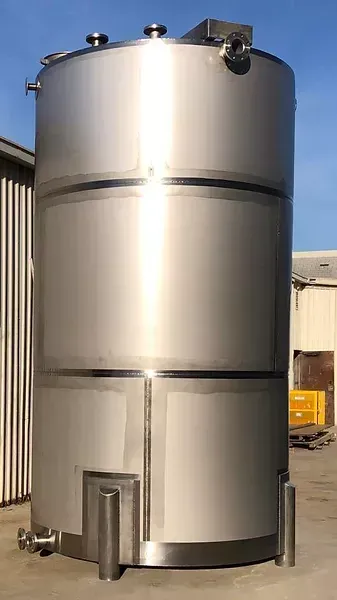 A large stainless steel tank is sitting in front of a building.