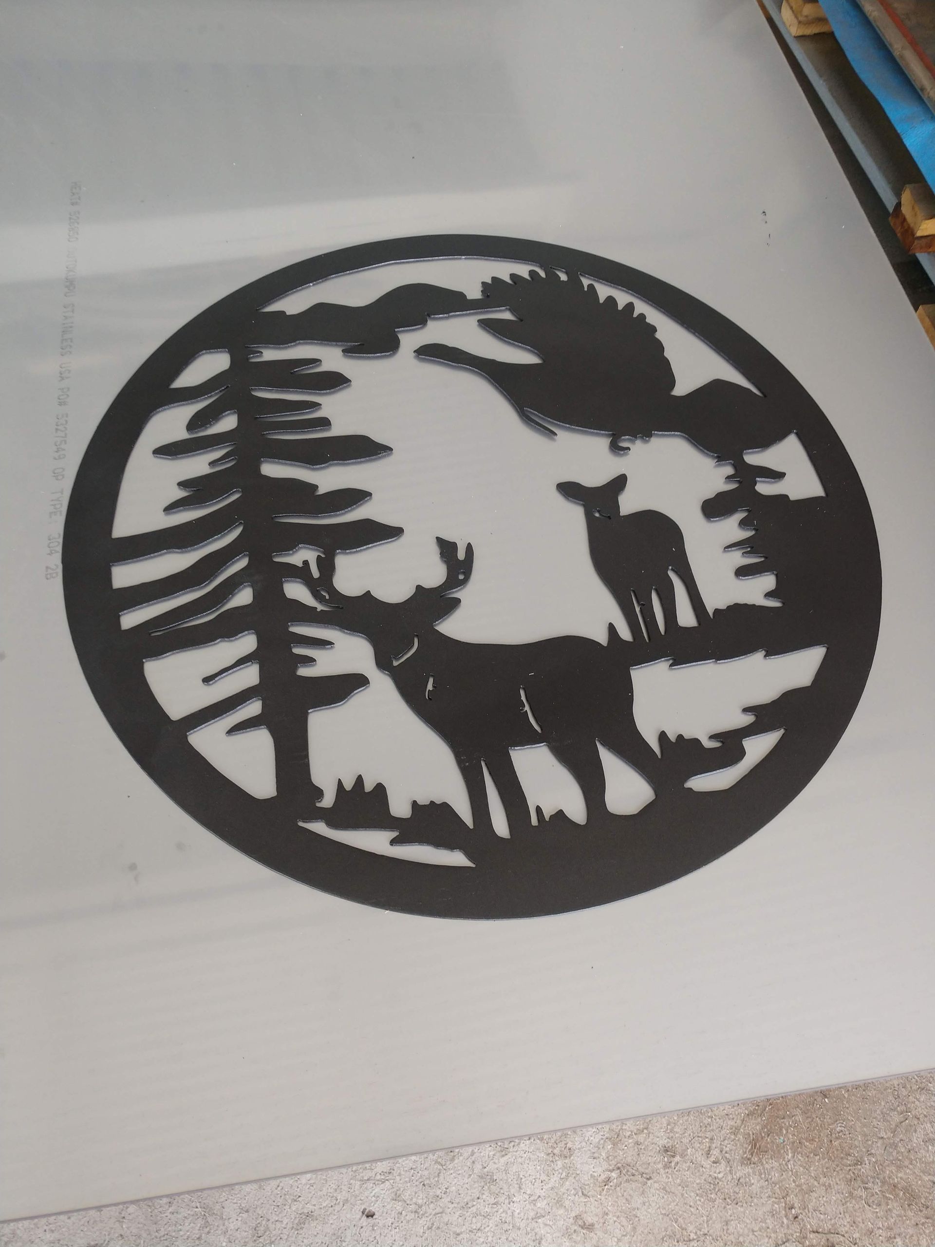 A silhouette of two deer in a circle with trees in the background.