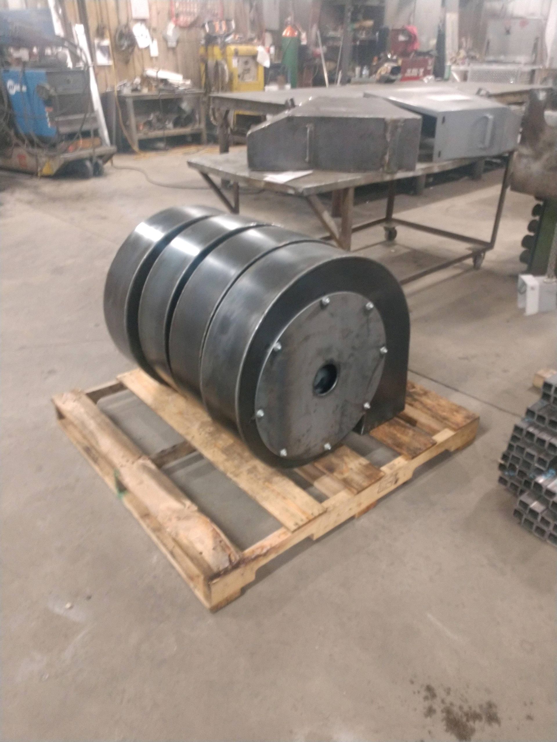 A large metal object is sitting on a wooden pallet in a factory.