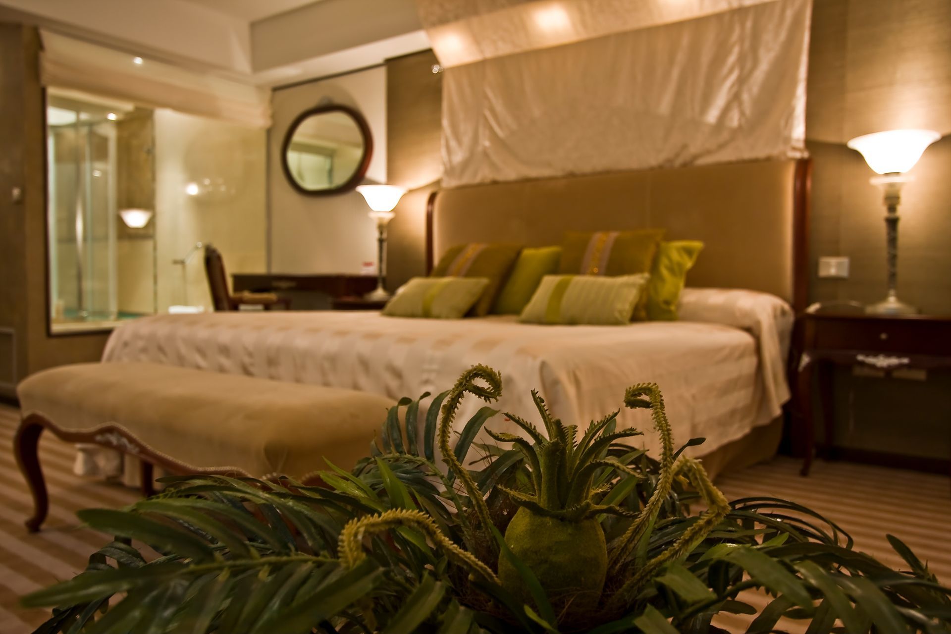 Un dormitorio con una cama grande y una planta en primer plano.