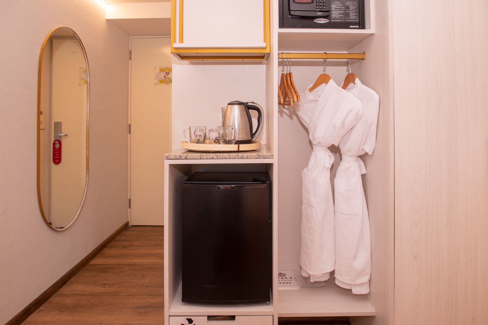 Una habitación de hotel con mininevera, microondas y espejo.