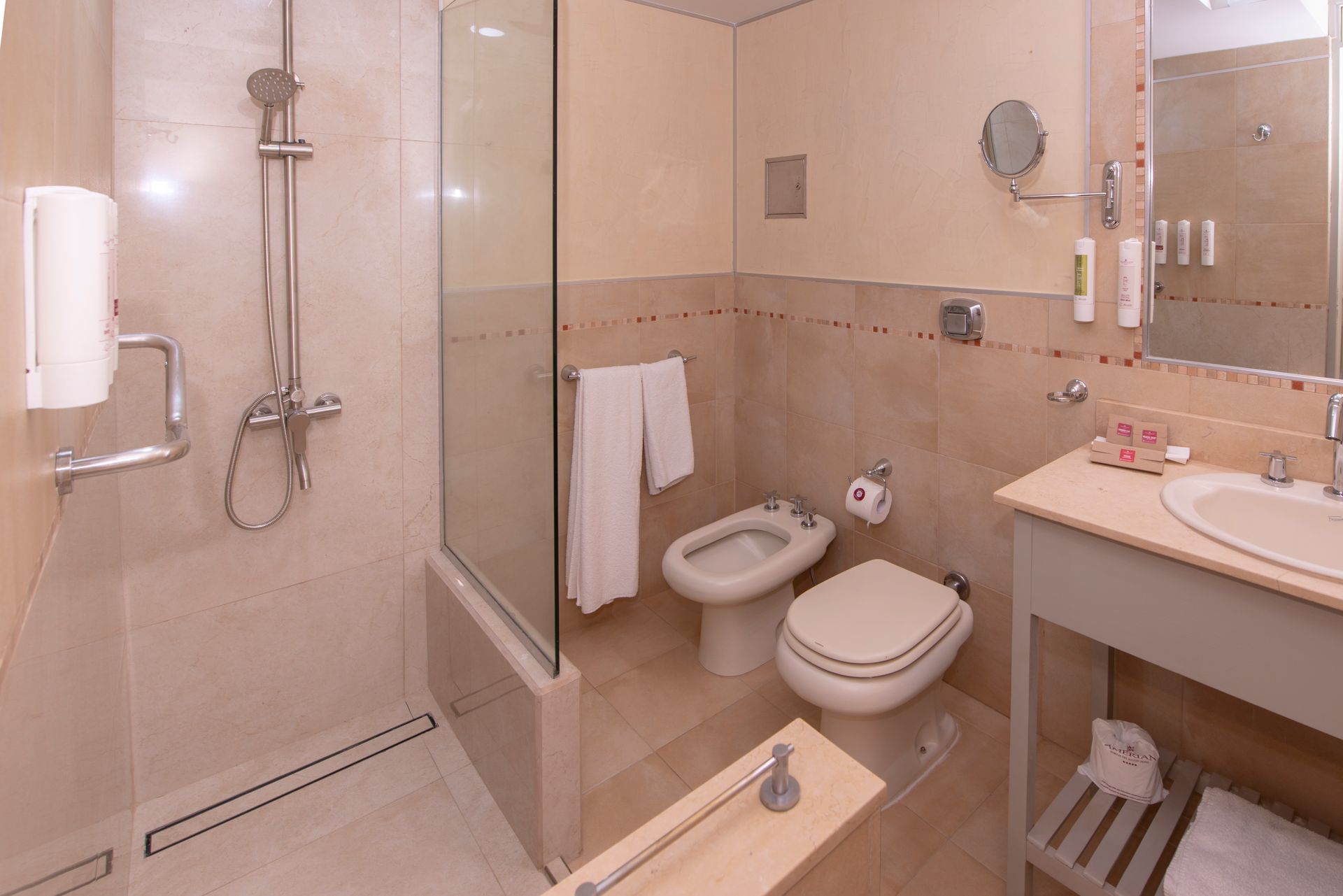 Un cuarto de baño con inodoro, lavabo, ducha y espejo.