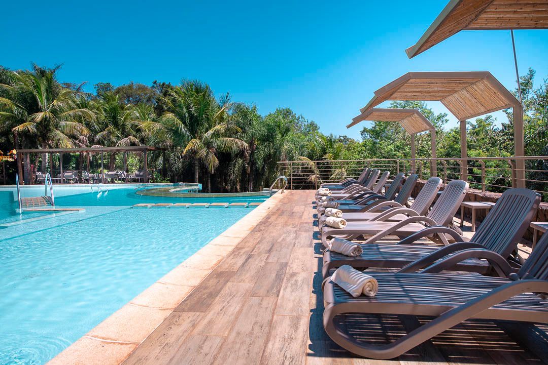 Una fila de tumbonas están alineadas junto a una piscina.