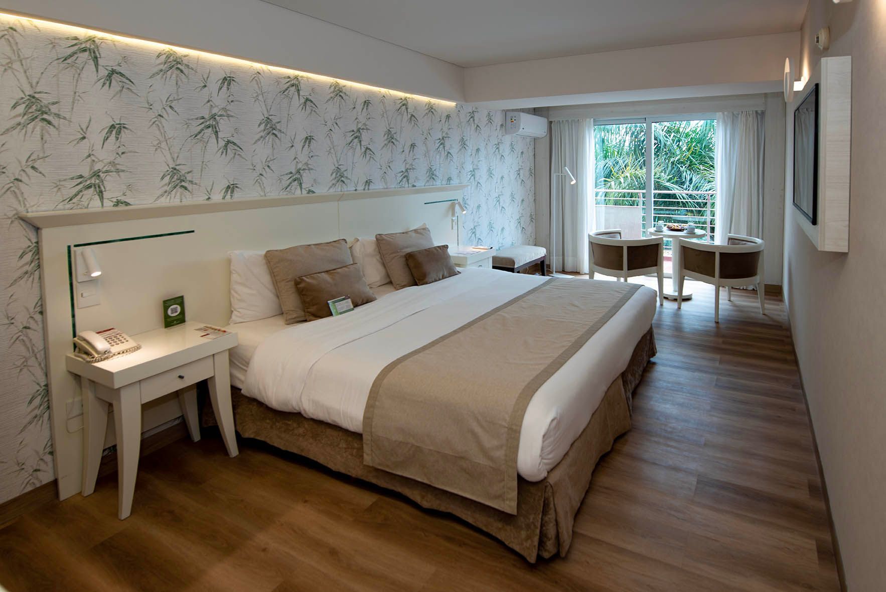 Una habitación de hotel con una cama king size, dos sillas, una mesa y un televisor.