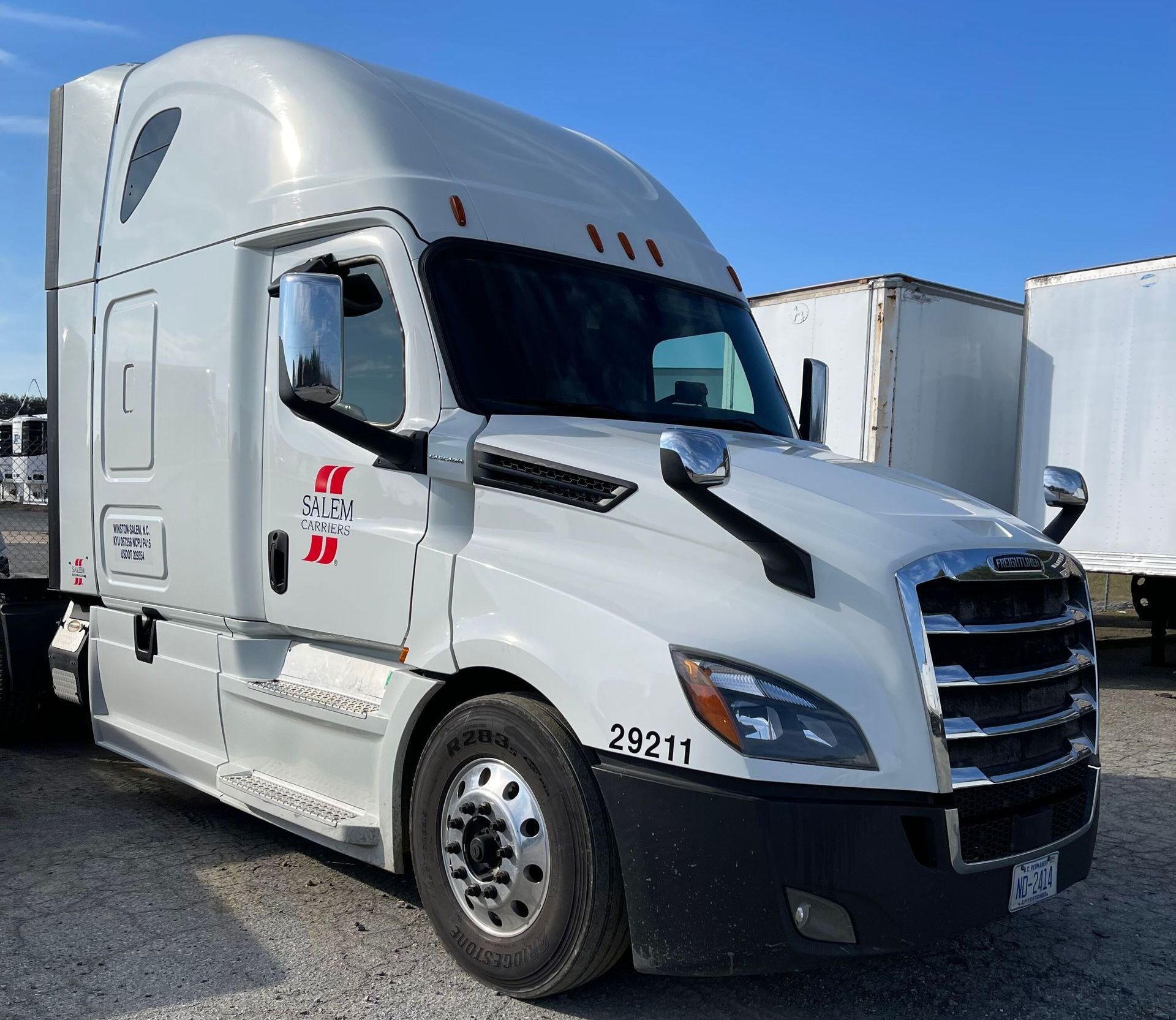 A white semi truck is parked in a parking lot.