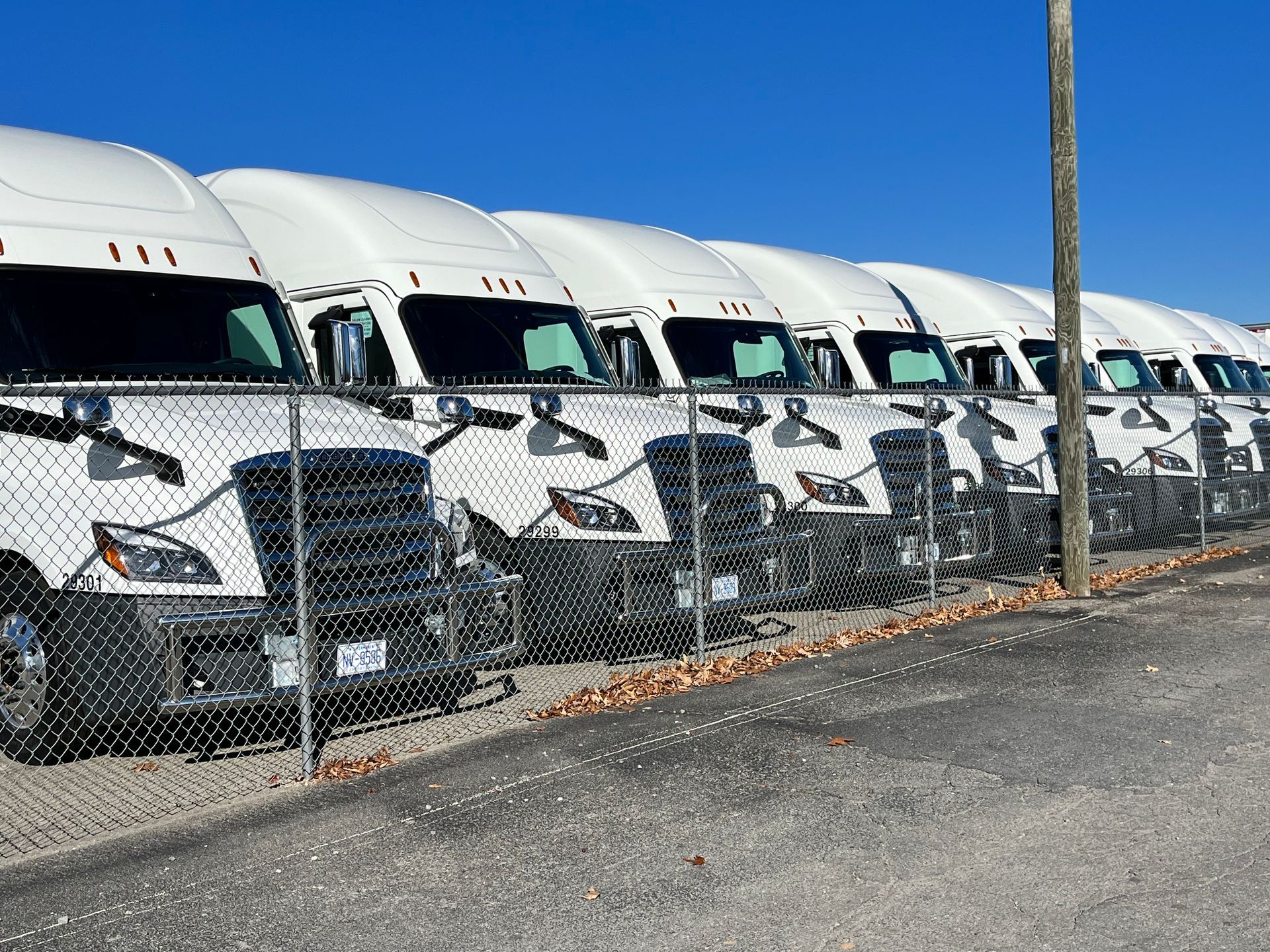 a row of Salem leasing semi trucks parked next to a chain link fence.