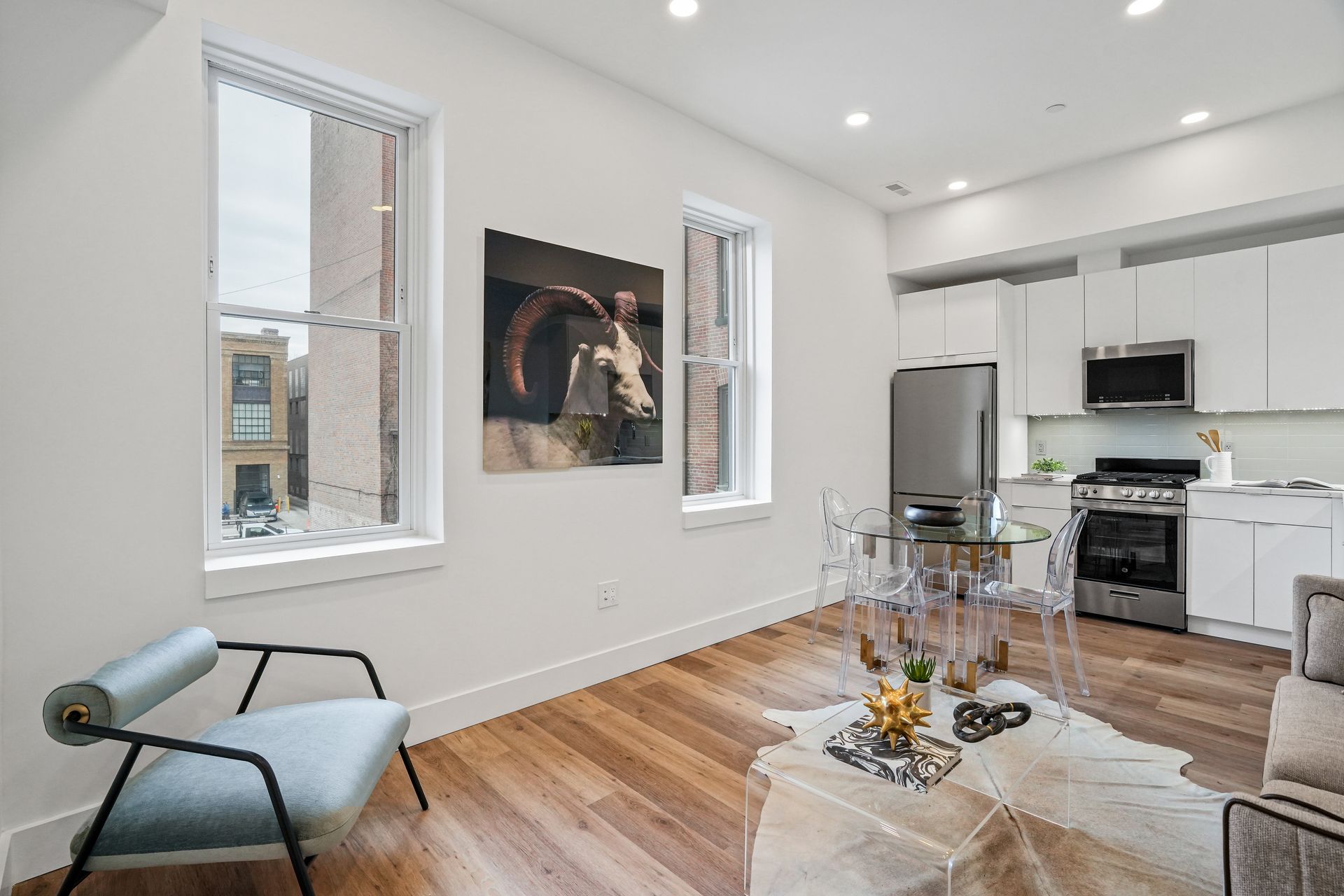 A living room with hardwood floors , a chair , a table and a painting on the wall.