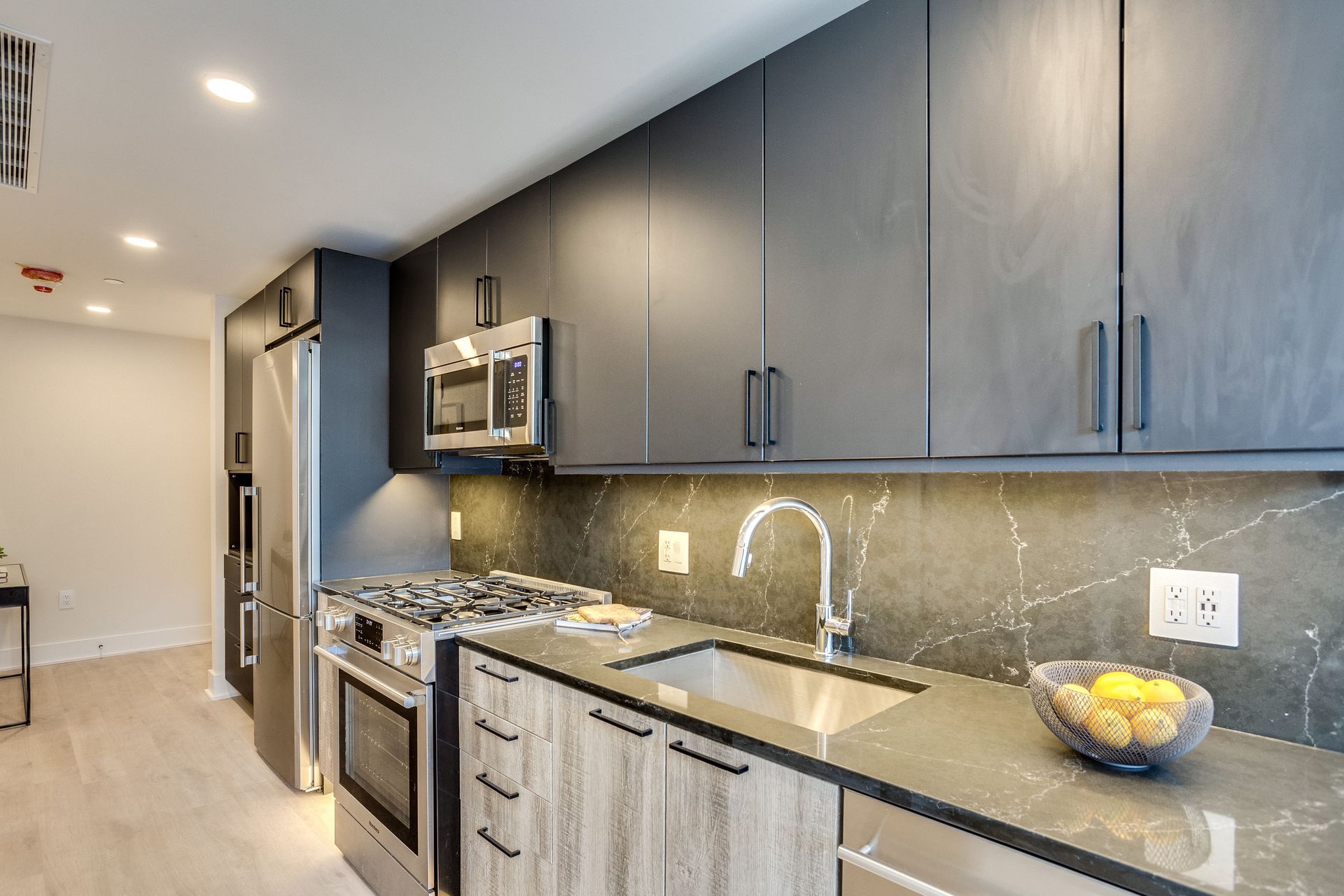 A kitchen with stainless steel appliances and a bowl of lemons on the counter.