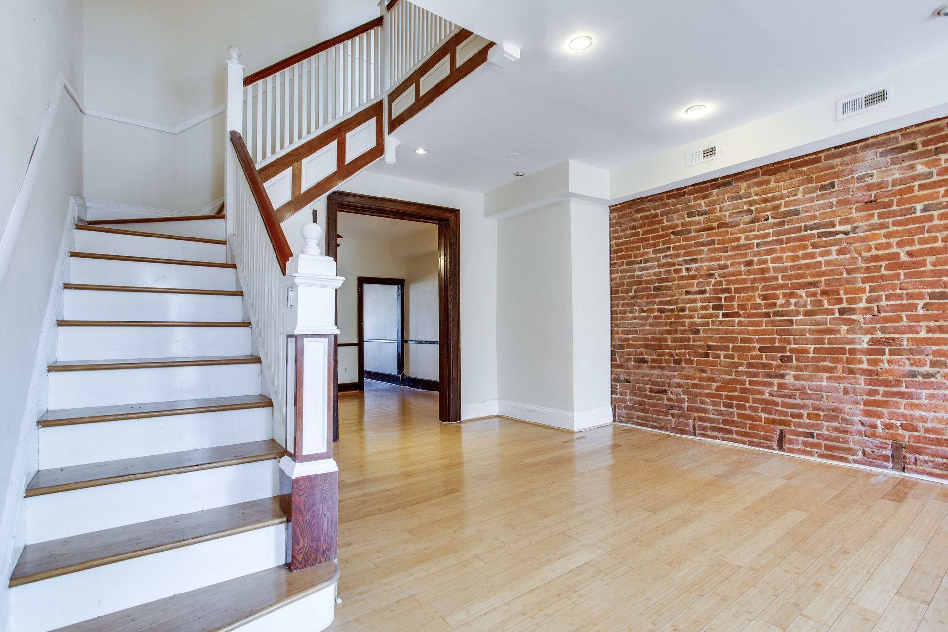 An empty room with a staircase and a brick wall.