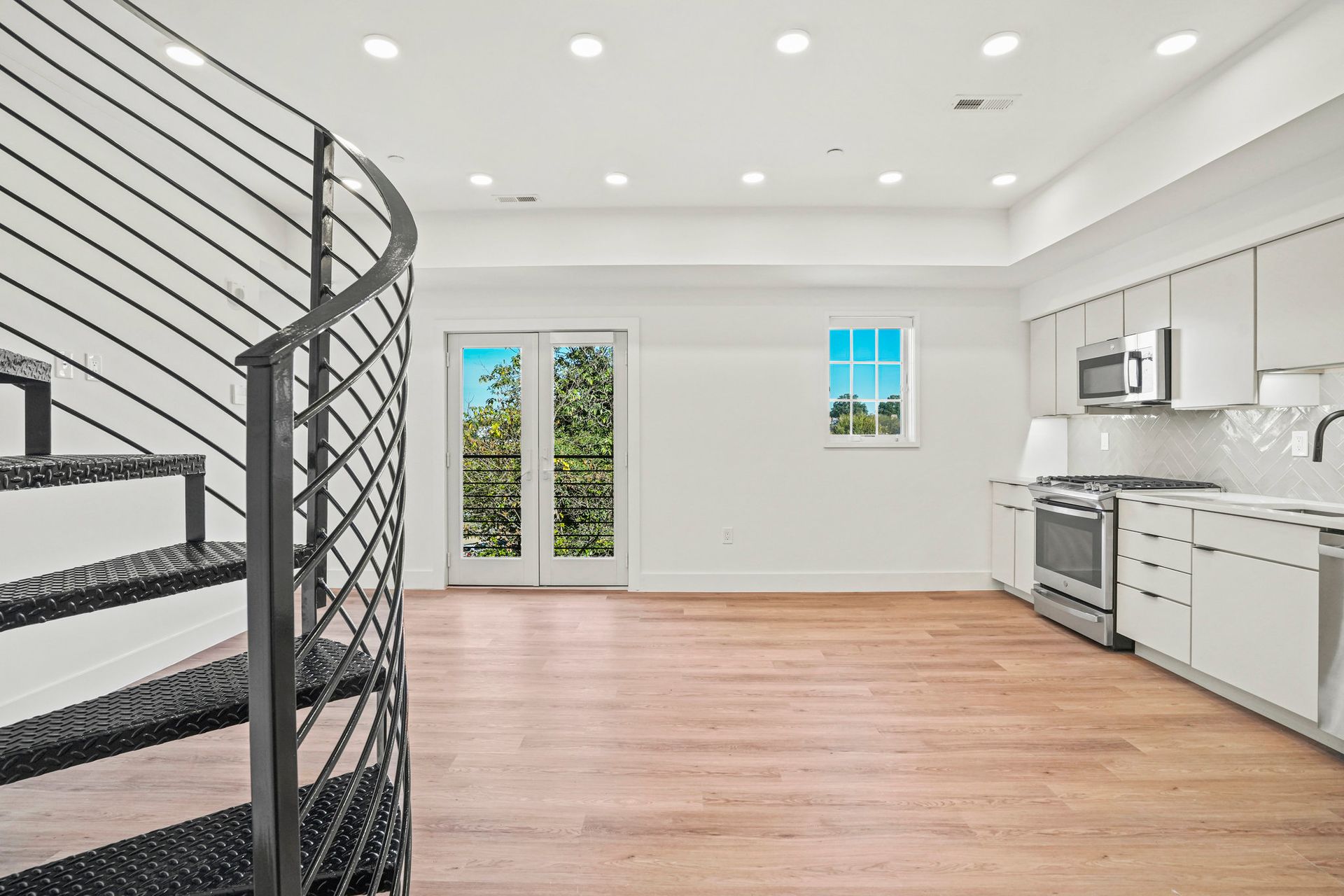 An empty kitchen with a spiral staircase leading to the second floor.