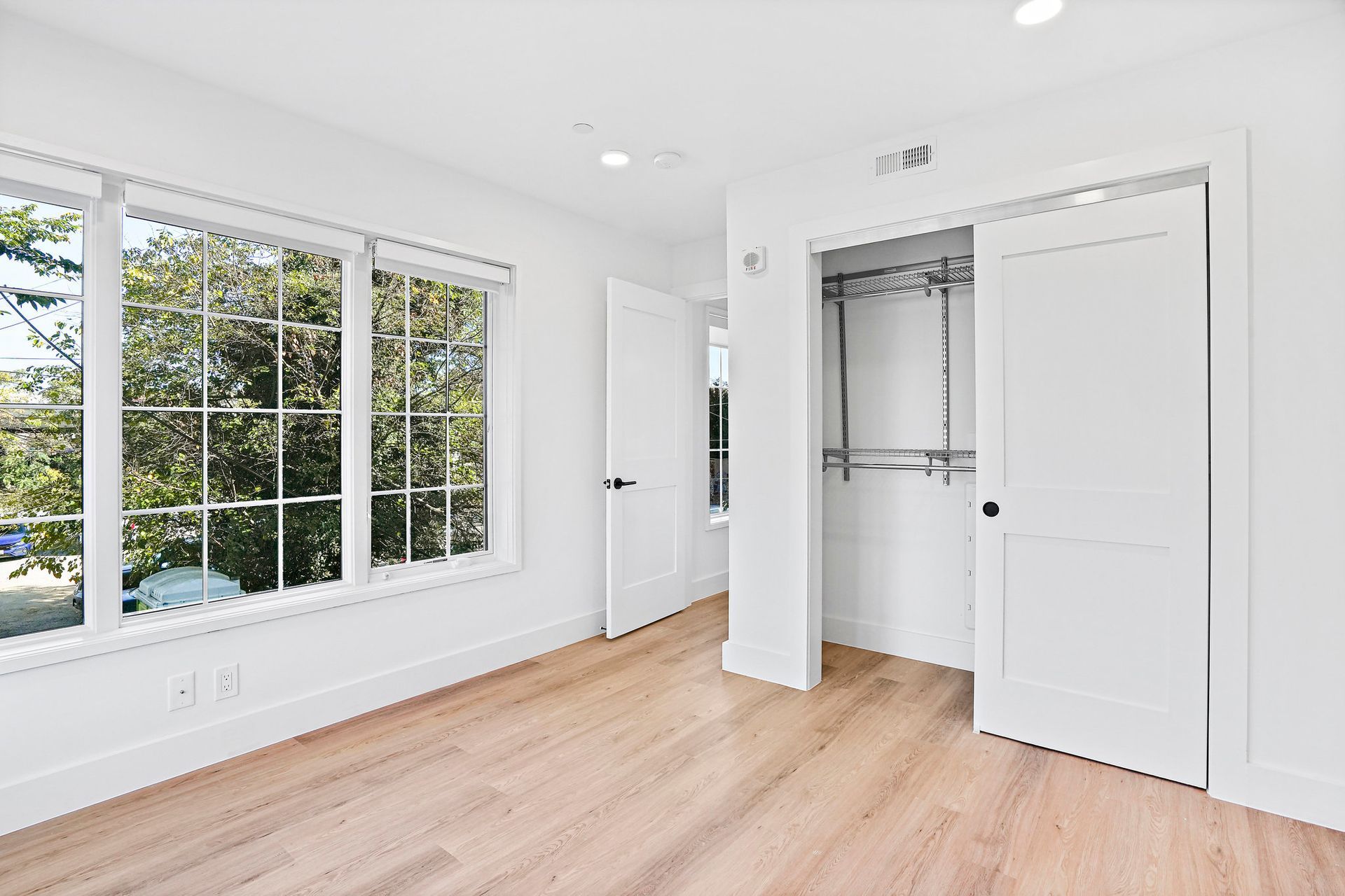 An empty bedroom with hardwood floors , white walls , and a walk in closet.