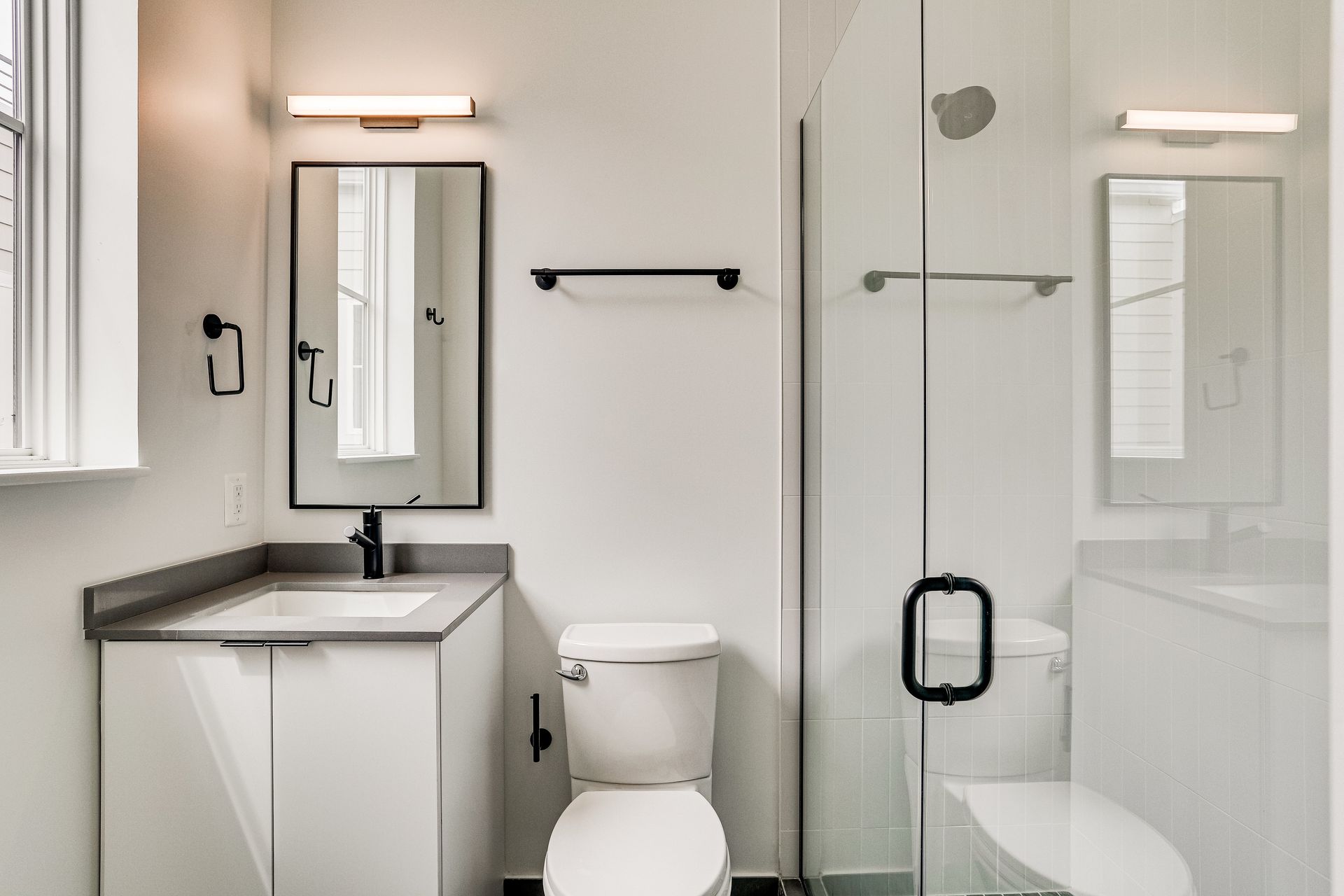 A bathroom with a toilet , sink , mirror and walk in shower.
