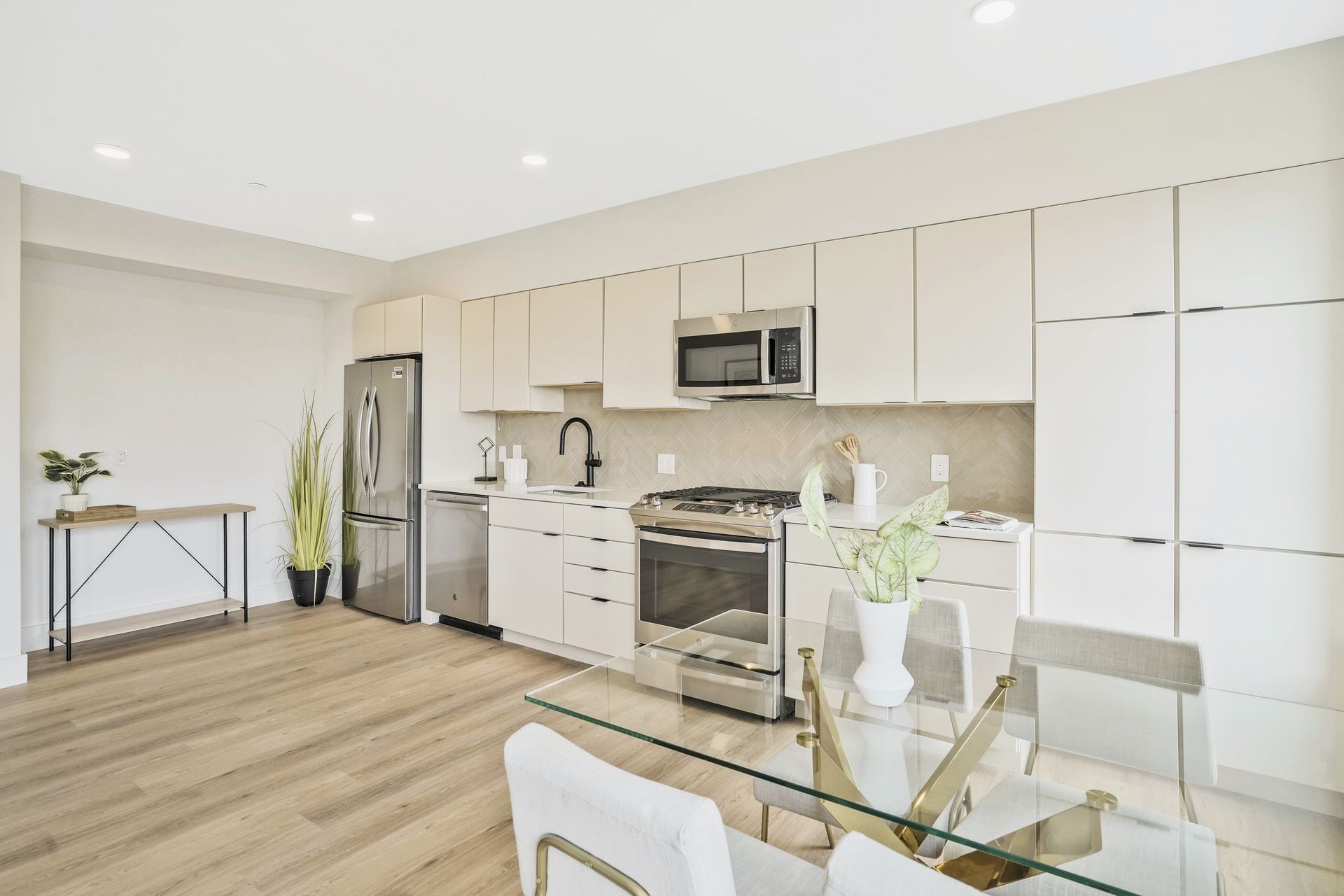 A kitchen with white cabinets and stainless steel appliances and a glass table.