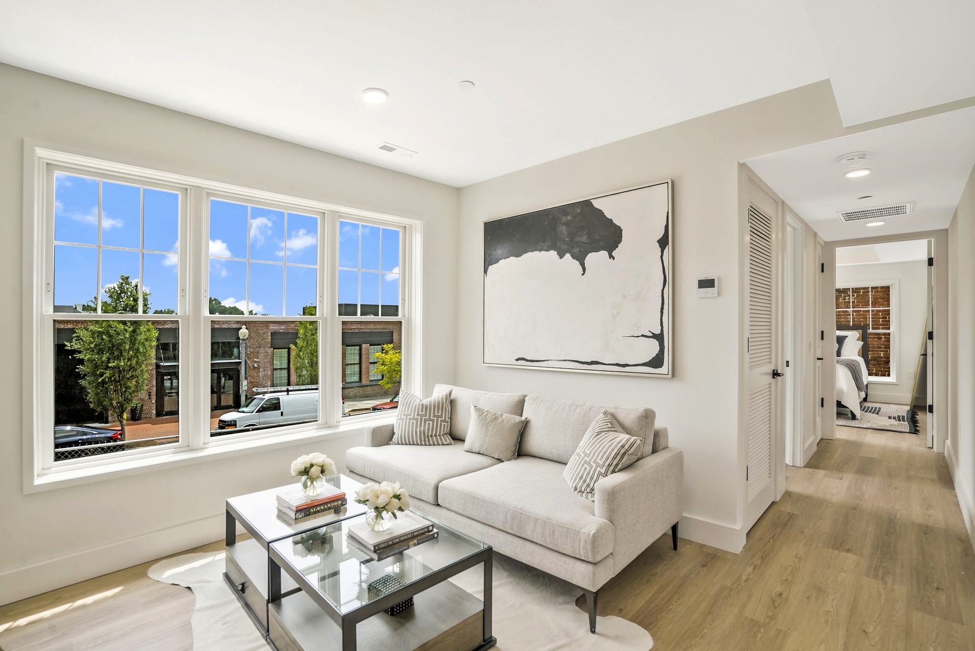 A living room with a couch , coffee table , and large windows.