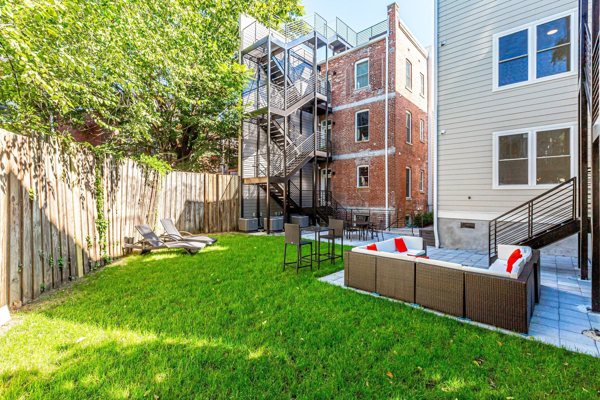 A backyard with a couch and chairs in front of a house.