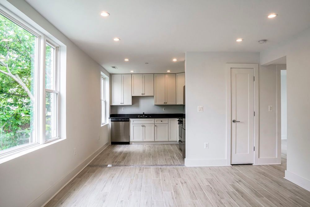 An empty living room with a kitchen in the background.