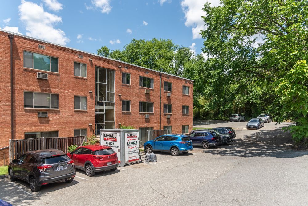 A row of cars are parked in front of a brick building.