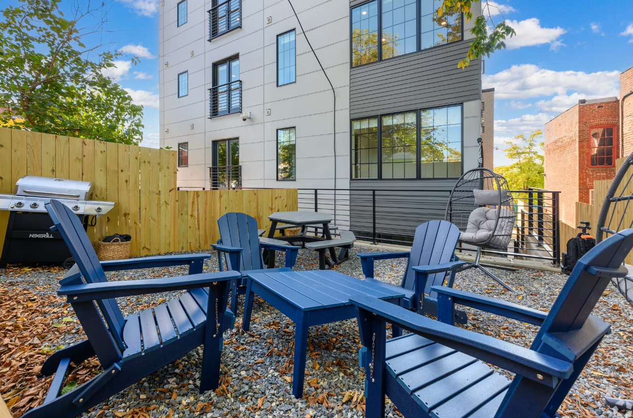 A patio with blue chairs and a table in front of a building.