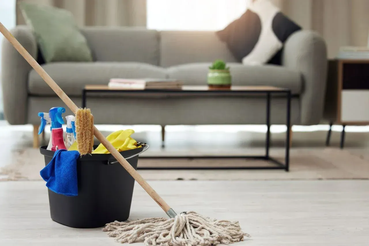 A man is cleaning a carpet with a vacuum cleaner in a living room.