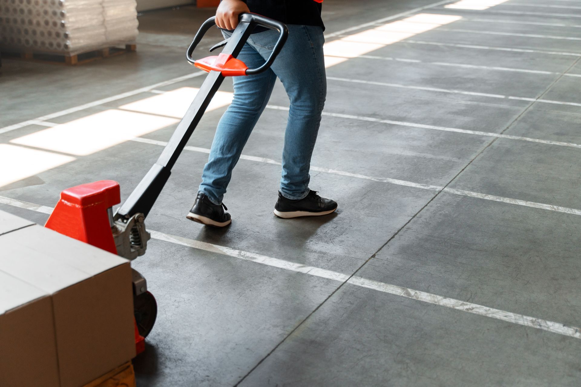 A professional cleaner in yellow gloves uses a steam extraction machine to clean a gray carpet in a living room.