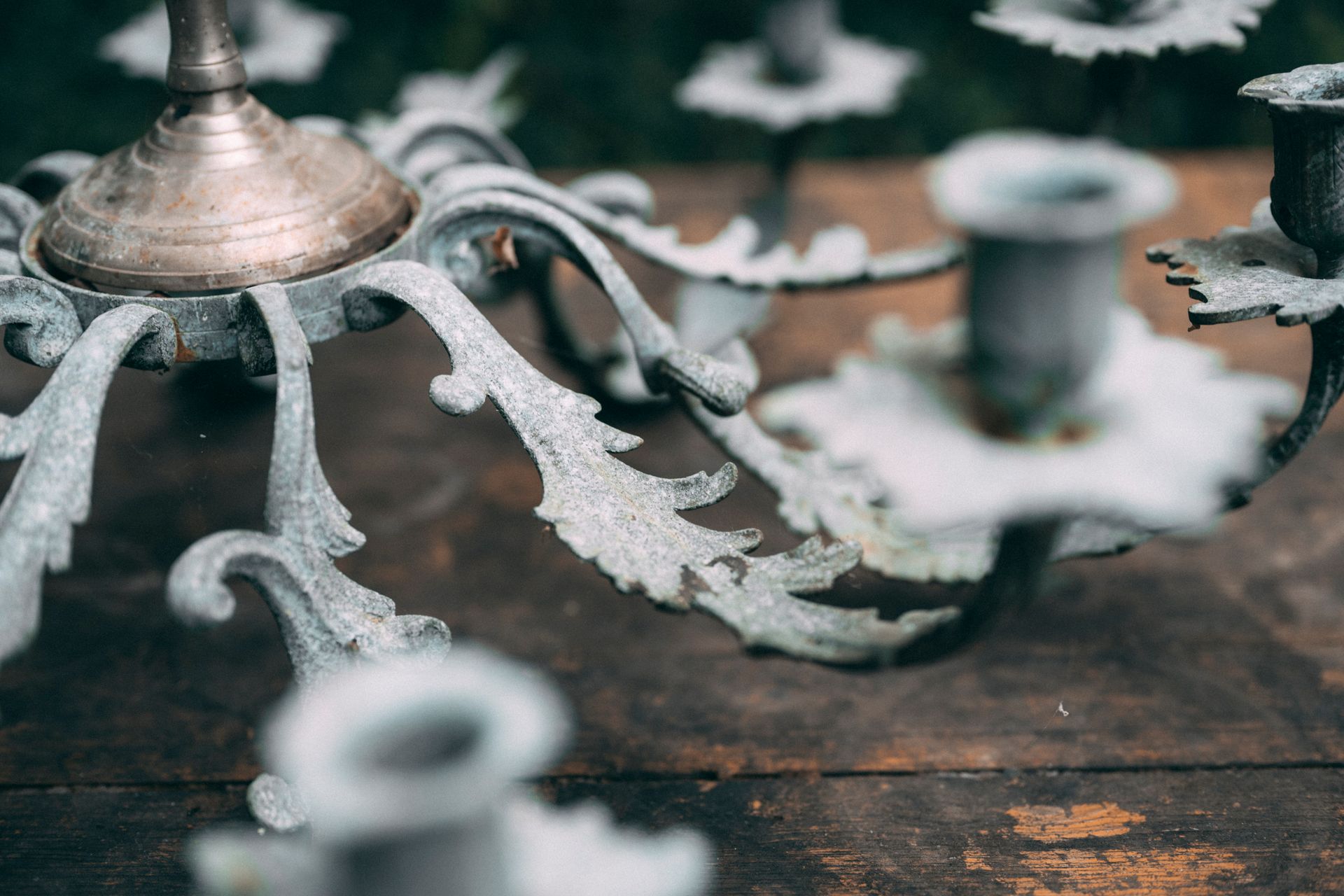 Primo piano di un candelabro in metallo decorato e invecchiato su una superficie di legno.