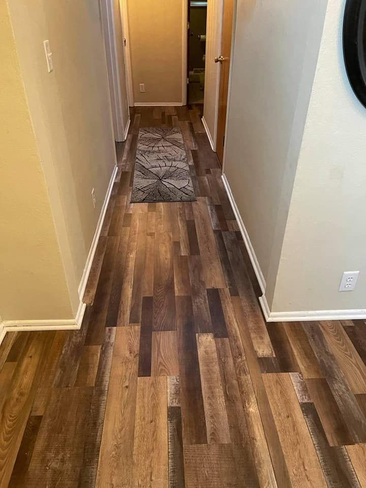 Narrow hallway with wood-look flooring and a patterned rug. Beige walls, white trim.