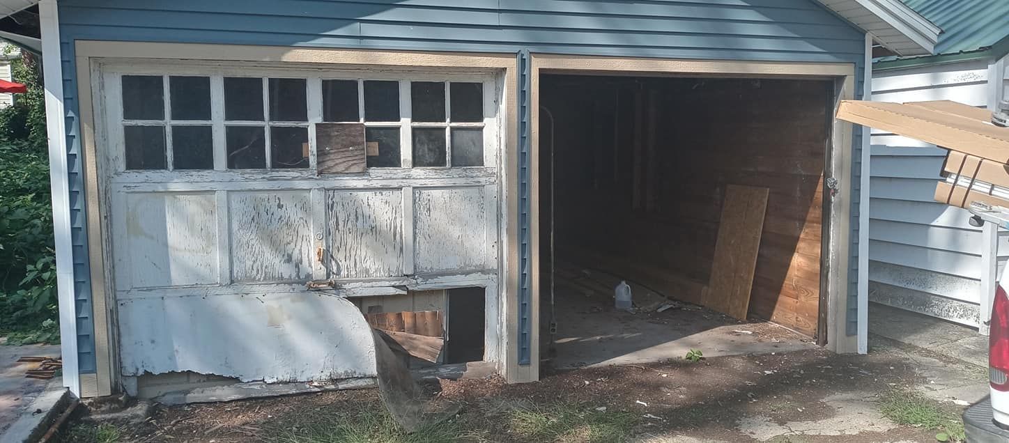 A dilapidated two-car garage with one door broken.