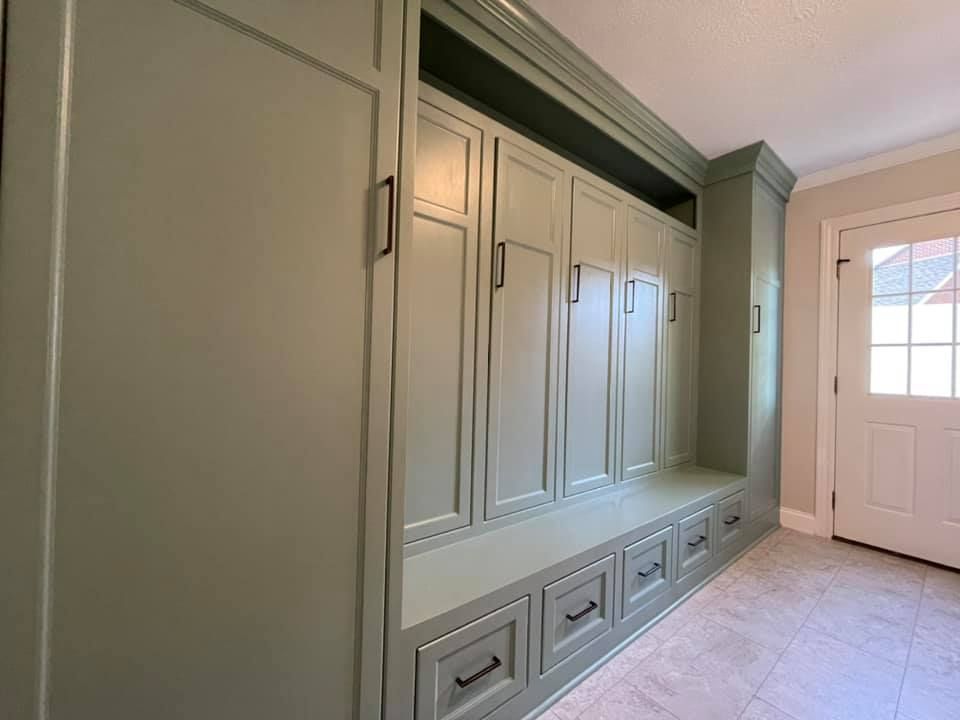 Green built-in storage unit with cabinets and drawers, near a white door and tile floor.