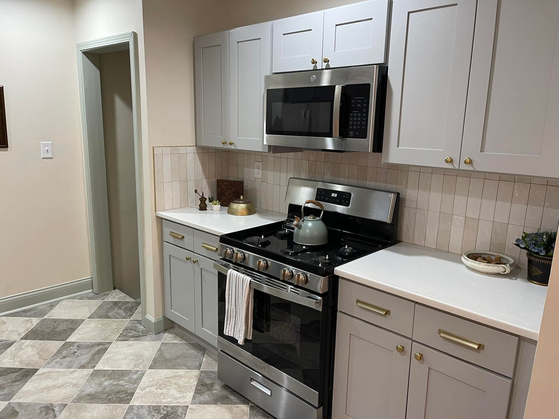 Kitchen with light gray cabinets, stainless steel appliances, and checkerboard floor.