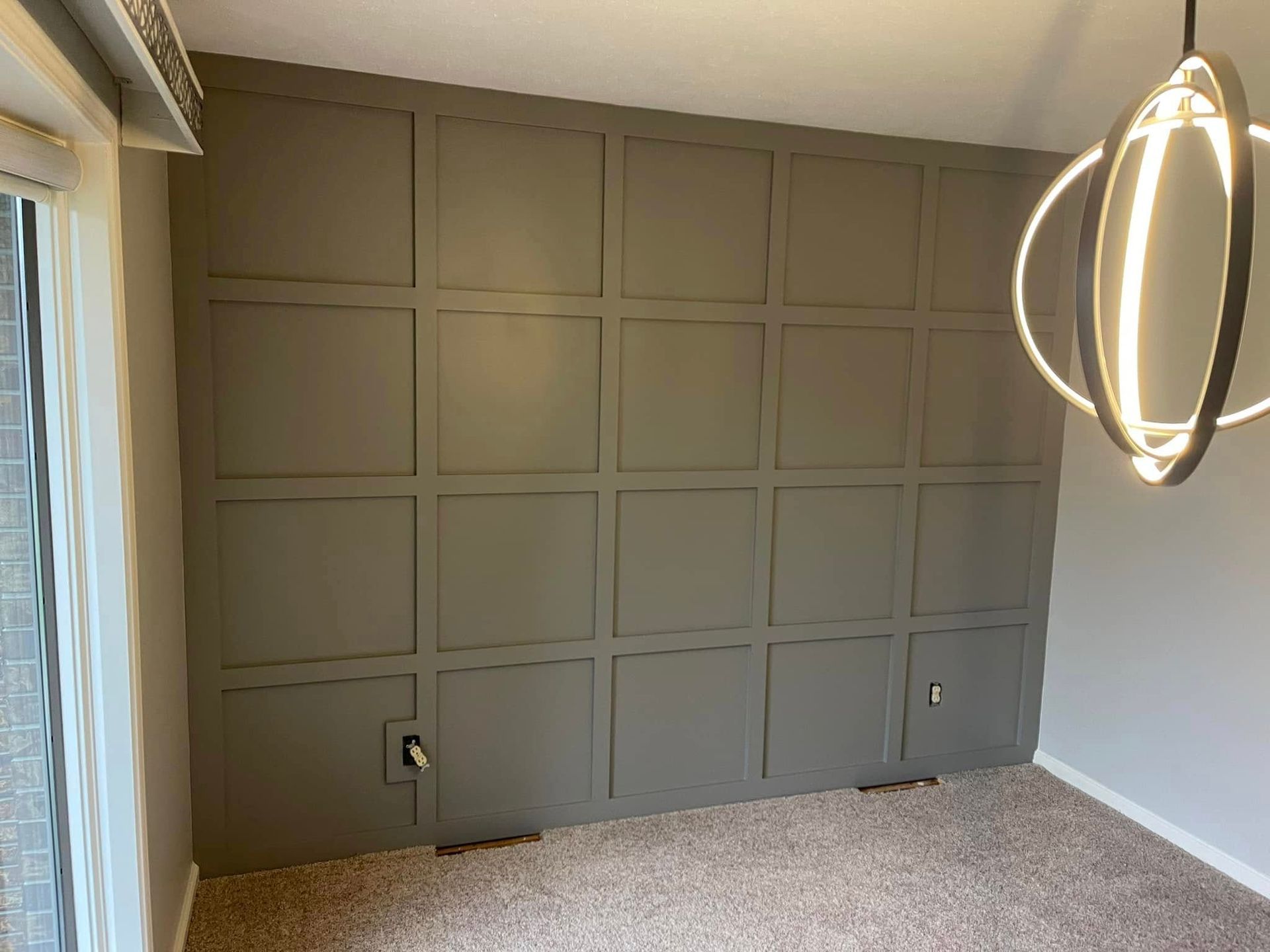 Gray paneled accent wall with electrical outlets and a modern light fixture.
