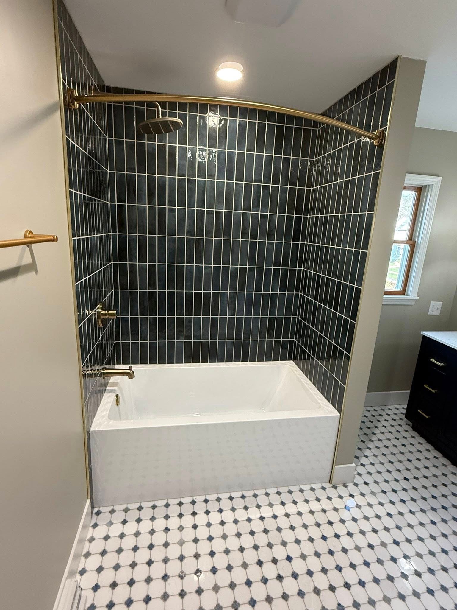 Bathroom with black and silver tile shower, white tub, and black and white floor tiles.