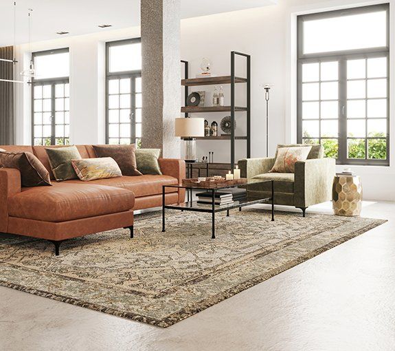 Living room with brown leather sectional sofa, green armchair, patterned rug, and large windows.